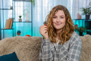 Altın Bitcoin BTC 'yi elinde tutan genç bir kadın. Kripto yatırım seçeneklerini incelikle analiz ediyor. Kanepede oturan beyaz saçlı kız finansal stratejinin dijital para birimi planladığını düşünüyor.