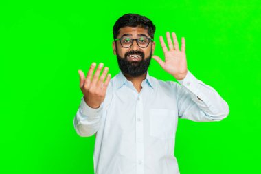 Hintli adam neşeli bir ifadeyle el sallıyor, birini daha yakına gelmeye ya da hoş geldin jesti ile içeri girmeye davet ediyor. Yeşil renkli arka plandaki Arap adam gülümseyerek dikkat çekiyor..