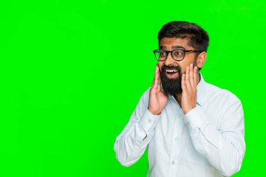 Hintli adam kaşlarını kaldırır ve şaşkınlıkla gözlerini açar, ellerini yüzüne yaklaştırır, çarpıcı haberlere tepki verir. Arap adam krom anahtarla izole edilmiş. Şok, sürpriz, inançsızlık, vay canına.