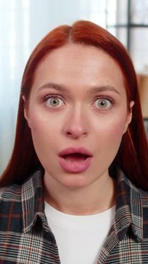 Beklenmedik bir şey gördükten sonra evde kaşlarını kaldıran ve ağzı açık duran genç bir kadın. Kanepedeki beyaz saçlı kız duygusal tepki veriyor, şok geçiriyor ve ani bilgilerle şaşkına dönüyor.