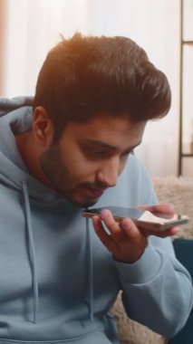 Kızgın kızgın sinirli Hintli genç adam hoparlör moduyla konuşurken tartışıyor sinirden bağırıyor. Hispanik, evdeki oturma odasındaki kanepede oturan memnun olmayan adamı gücendirdi..