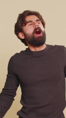 Çok çalışan Lübnanlı genç adam uykusuzluktan uykusuz, ilgisiz tembel, uykusuzluktan ağzı açık kalmaktan sıkılmış. Yorgun Hintli adam, stüdyo bej arka planında izole edilmiş.