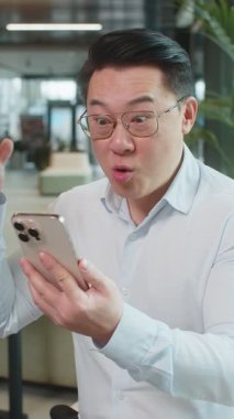 Akıllı telefon üzerinde çalışan mutlu, şaşkın genç işadamı piyango kazanan bir galibiyet oyunuyla şok oldu. Kariyer başarısı iyi haber. Ofis otel lobisinde oturan gömlekli, heyecanlı, olgun bir adam..