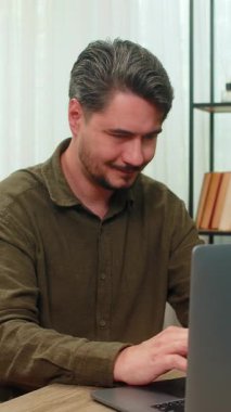 Evde çalışan orta yaşlı bir adam dizüstü bilgisayar raporunda büyük kazanç elde ettiği için el çırpıyor. Masadaki genç adam kontrat başarısını kutluyor. Gülümsüyor. İleride büyük bir kariyer artışı seziyor.