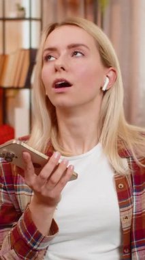 Şaşırmış kadın evdeki koltukta otururken kablosuz kulaklıklardan sesli mesaj dinliyor, şaşırmış. Sarışın kız duygu ve ilgiyle tepki verir, beklenmedik bir sese odaklanırken başını sallar..