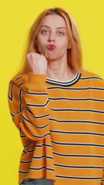 Saldırgan, beyaz, sarışın kadın kameraya karşı dövüşmeye çalışıyor, yumruklarını sallıyor, ifadeyle boks yapıyor, cezalandırıyor, tehdit ediyor, taciz ediyor, öfkeden kuduruyor. Sarı arka planda izole edilmiş genç bir kız.