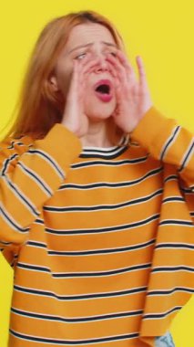 Beyaz tenli genç bir kadın, el ele tutuşup yüksek sesle bağırıyor, bağırıyor, bağırıyor, indirimli satış ilanı veriyor. Sarı arkaplanda izole edilmiş kız