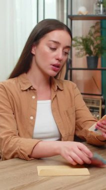 Evdeki genç kadın avroya ait nakit paraları sayıyor, gelecekteki satın alma planlarının bir kısmını zarfa atıyor. Beyaz kız sessizce gülümsüyor. Para ve kişisel finansal hedefler konusunda kendini güvende hissediyor..