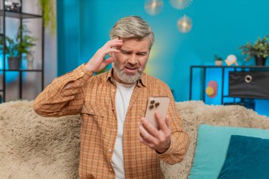 Beyaz, olgun bir adam evdeki kanepede oturuyor, elinde akıllı telefon ve stres belirtileri gösteriyor. Orta yaşlı bir adam kötü haber mesajı alır. Umutsuzluk ve yorgunluk hisseder. Yorgun görünür.