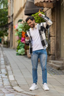Cep telefonu kutlaması yapan Hintli genç adam iyi haber kazandı, piyango büyük ikramiyesi kazandı, açık havada dağıttı. Şehir caddesinde İspanyol bir gezgin. Kasaba yaşam tarzları.