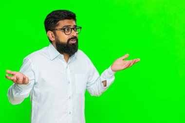 Hintli bir adam omuz silkiyor iki elini de yüzünde şaşkın bir ifadeyle kaldırıyor, belirsizlik ya da kafa karışıklığı içeren beklenmedik bir sonuç. Düşünceli ifadeli, krom anahtarlı Arap bir adam.