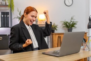 Merkez ofisteki genç iş kadını dizüstü bilgisayarı açtı ve derin bir neşe nefes alma projesi için onay aldı. Masadaki serbest çalışan kız zafer topukluları kariyerinin yükselmesini kutluyor.