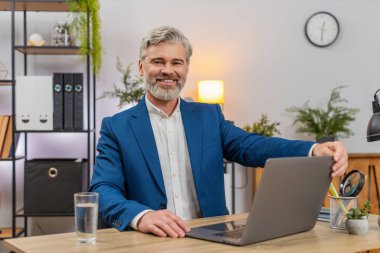 Merkez ofisteki orta yaşlı işadamı, üretken iş akışını hızlandırmak için dizüstü bilgisayar açıyor. Masa tipleri toplantısındaki serbest çalışan eleman iş bitiş tarihlerini takip ediyor, çıktıyı artırıyor..