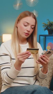 Kafkasyalı gülümseyen neşeli kadın kanepe akıllı telefon ve kredi kartıyla dijital ödemeyi tamamlıyor. Başarılı bir alışveriş, modern yaşam tarzında konfor sağladı. Güvenli alışveriş rahatlığı.