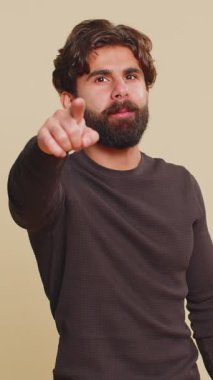 Seni seçiyorum. Hintli genç adam kamerayı gösterip neşeli bir ifadeyle bakıyor, seçim yapıyor, yön gösteriyor. Bej renkli stüdyo arka planında tek başına sırıtan İspanyol Hintli adam..