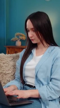 Genç, mutlu bir kadın duygusal olarak beklenmedik bir başarıyı laptopta kutluyor ve ağzı şaşkın bir inançsızlıkla kaplanıyor. Kanepede el sallayan beyaz kız, güzel ve şok edici haberlere tepki veriyor.