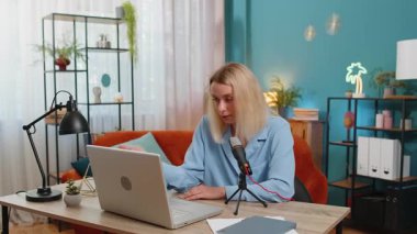 Mutlu blogcu kadın podcast yapıyor, atölye çalışması yapıyor, webinar yapıyor. Genç beyaz kız mikrofon ve dizüstü bilgisayar kamerasında konuşuyor, video görüşmesi yapıyor, oturma odasındaki ofiste tartışıyor..