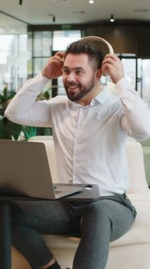 Modern ofis lobisinde oturmuş, kablosuz kulaklıkla enerjik disko müziği dinleyen neşeli, beyaz sakallı iş adamı. Yönetici masadaki dizüstü bilgisayarla dinleniyor..