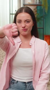 Genç bir kadın evdeki kanepede oturur ve hoşnutsuzluğunu ifade etmek için baş parmağını kaldırır. Kafkasyalı kız açıkça onaylamıyor ve memnuniyetsizliğini açıkça ifade ediyor.