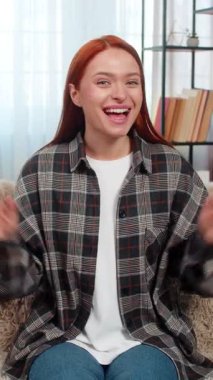 Genç bir kadın kameraya el sallıyor ve gülümsüyor. Dostane ve neşeli bir şekilde merhaba diyor. Kanepede beyaz saçlı bir kız internetten birini selamlıyor. Dijital sosyal etkileşim anının tadını çıkarıyor.