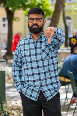 Hoşlanmamak. Üzgün Hintli sakallı adam işaret dilini gösteriyor, hoşnutsuzluğunu dile getiriyor, tatminsiz kötü işler yapıyor, açık havada hata yapıyor. Şehir sokağındaki hoşnutsuz İspanyol adam. Dikey