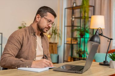İnternetteki video dersine ya da ofis bilgisayarındaki laptop toplantısına katılırken not alan ya da not alan genç iş adamı. Webcam 'e bakan Serbest Çalışan Destek Servisi.