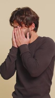 Buna bakmak istemiyorum, çok kötü. Hintli sakallı adam gözlerini kapatıyor. Durma hareketi gösteriyor. Kafası karışmış, utangaç, izlemekten korkuyor. Genç yetişkin erkek çocuk bej renkli stüdyo arka planında tek başına izole edilmiş..