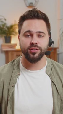 Kendine güveni tam, beyaz bir adam evdeki koltukta otururken kulaklık takıyor, serbest çalışıyor, çağrı merkezi, destek operatörü yardım hattı, müşteri ya da iş arkadaşıyla konuşuyor, iletişim desteği kullanıyor..