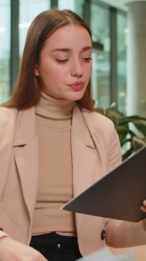 Beyaz tenli genç iş kadını belgelerle çalışıyor, bilgileri analiz ediyor, gazete okuyor mali raporları hazırlıyor. Genç bayan girişimci ofis lobisindeki grafik belgelerini analiz ediyor..