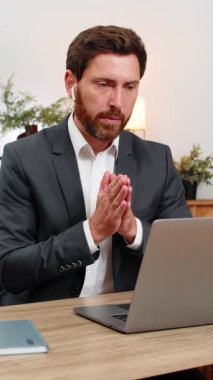 Merkez ofisteki orta yaşlı iş adamı, kablosuz kulaklık ve el sallayarak bilgisayar konferansına katılıyor. Masadaki serbest çalışan adam güler ve toplantı sırasında not defterine not alır..