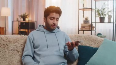 Kızgın kızgın sinirli Hintli genç adam hoparlör moduyla konuşurken tartışıyor sinirden bağırıyor. Arap, evdeki oturma odasındaki kanepede oturan memnun olmayan adamı gücendirdi..