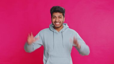 Komik şakacı Hintli adam aptalca yüz ifadeleri yapıyor, suratını buruşturuyor, dalga geçiyor, dil gösteriyor, aptalca bir ifade takınıyor. Komedyen Arap adam pembe arka planda izole edilmiş. İnsan yaşam tarzları