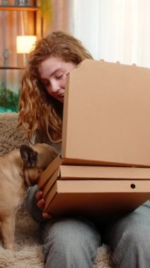 Beyaz saçlı genç bir kadın evdeki kanepenin üzerinde pizza kutularını açıyor ve heyecanla lezzetli yemeklere gülümsüyor. Pug dog ısırıkları, yemek dağıtım sırasında sahibine neşeli anlar yaşatır..