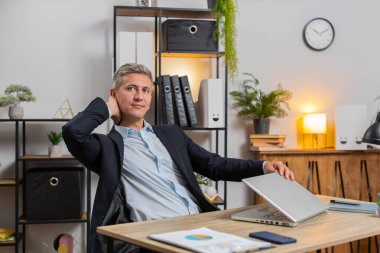 Genç işadamı ofis projesini bitirdikten sonra bilgisayarını kapatıp masa başında oturuyor. Kafkasyalı serbest çalışan, modern ofiste uzaktan kumandalı iş yapıyor. Netbook bilgisayarında gezinme, E-öğrenme İnternet.