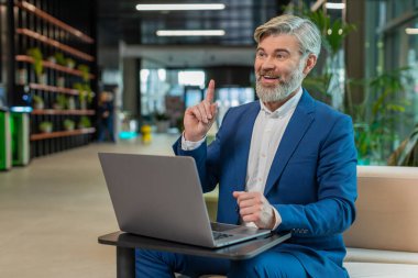 Evreka. Düşünceli, zeki, beyaz, takım elbiseli bir iş adamının dizüstü bilgisayarını kullanarak parmağını kaldırarak yaratıcı bir plan yaptı. Otel lobisindeki ilham verici motivasyonla heyecanlandı..