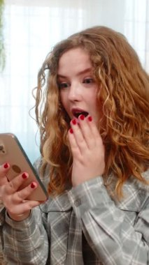 Evde cep telefonunu kaydıran genç bir kadın, haber, indirim ya da Kafkasyalı bayanı temsil eden kazanan sonuç için heyecanlanıyor. Kanepedeki kızıl saçlı kız haykırıyor. Şaşırmış, sevinçli bir kutlama reaksiyonu gösteriyor.