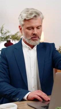 Merkez ofisteki orta yaşlı işadamı, üretken iş akışını hızlandırmak için dizüstü bilgisayar açıyor. Masa tipleri toplantısındaki serbest çalışan eleman iş bitiş tarihlerini takip ediyor, çıktıyı artırıyor..