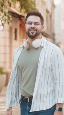 Kameraya bakan, dinlenen, rahatlayan mutlu beyaz bir gencin portresi. Dışarıda iyi haberlerin mutlu ifadesi. Şehir caddesinde sakallı turist. Kasaba yaşam tarzları