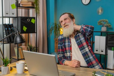 Beyazların yorgun kıdemlisi ev işyerinde dizüstü bilgisayarla çalışırken omurga kası ağrısı çekiyor. Çok çalışıyorum. Sakallı serbest çalışan büyükbaba masaj yaparak acıyı dindirmeye çalışıyor..