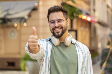 Gibi. Mutlu adam başparmağını kaldırır bir şeye katılır ya da olumlu cevap verir reklamlar iyi fikir geri bildirimlerini sever, başarı zaferini kutlar. Şehir caddesinde duran adam turist.