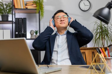 Mutlu, rahat Asyalı iş adamı ev bilgisayarında çalışıyor kulaklık takıyor ve en sevilen enerjik disko müziği ve dansı dinliyor. Serbest çalışan Çinli adam dinleniyor, mola veriyor.