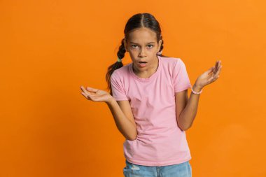 - Ne? - Neden? Öfkeli bir ifadeyle elini kaldıran genç bir kız, sorunların neden inançsızlığı gösterdiğini soruyor. Çocuk 10 yaşında, turuncu arka planda.