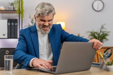 Merkez ofisteki orta yaşlı işadamı bilgisayarın donuk hata ekranına bakıyor ve kapak iç çekişini tekrar engelliyor. Masadaki serbest çalışan adam, kaybedilen ilerlemeyi telafi etmek için zamanı belirleyen yedek planı gözden geçiriyor..