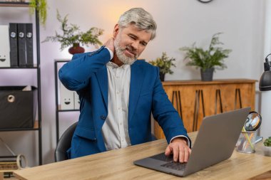 Merkez ofisteki orta yaşlı işadamı aniden boğazını sıkıyor. Derin bir acı hissediyor. Acilen rahatlaması gerekiyor. Masadaki serbest çalışan adam kaslarını esnetiyor. Rahatsızlık geçsin diye masaj yapıyor..