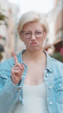 Hoşnutsuz, kötü bir fikre tepki veren, kötü kaliteden memnun olmayan beyaz bir kadın, el salla, başını salla hayır, reddet fikri, evlenme teklifini sevme. Genç sarışın bayan gezgin şehir caddesinde