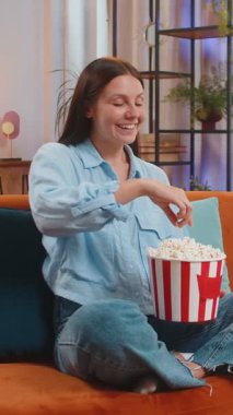 Heyecanlı genç bir kadın turuncu koltukta oturup patlamış mısır yiyor ve evde ilginç TV dizileri, spor oyunları, filmler, çevrimiçi sosyal medya filmleri izliyor. Kız ev eğlencesinden hoşlanıyor.