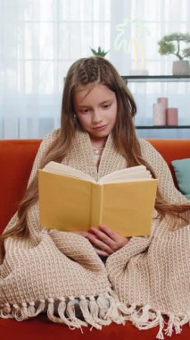 Genç beyaz çocuk battaniyeye sarılıp rahatlıyor ilginç kitaplar okuyor sayfalarca gülümsüyor edebiyattan keyif alıyor rahat bir kanepede dinleniyor. Evdeki oturma odasındaki kanepede oturan mutlu kız..