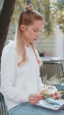 Mutlu zengin kadın dizüstü bilgisayar kazananı zaferini kullanıyor. Avro banknotlarında nakit para hayranı olarak şehir parkında oturuyor. Genç bayan turist kız çevrimiçi alışveriş bütçesi planlıyor.