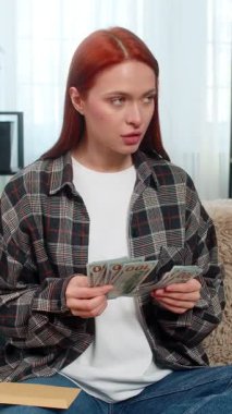 Evde para sayan genç bir kadın ve tatmin olmuş bir gülümsemeyle zarfa bir parça yerleştiriyor. Kafkasyalı kızıl saçlı kız kanepe planlama bütçesinde sorumlu ve duygusal olarak kendine güveniyor.