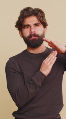 Lübnanlı genç bir adamın zaman aşımı jesti göstermesinden bıktım. Limit ya da dur işareti, baskı yok. Daha fazla zamana ihtiyacım var. Hintli Hintli adam stüdyo bej arka planında izole edilmiş..